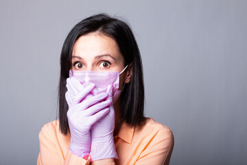 brunette woman in peach colored shirt, pink medical mask and gloves