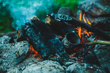 Vivid smoldered firewoods burned in fire close-up. Atmospheric warm background with orange flame of...