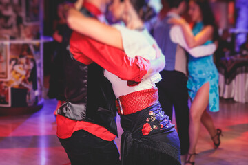 Couples and women wearing red skirts and dress dancing traditional gypsy dance in the ballroom hall