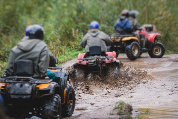 Fototapeta na wymiar Group of riders riding atv vehicle on off road track, process of driving ATV vehicle, all terrain quad bike vehicle, during offroad competition, crossing a puddle of mud