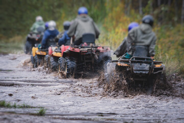 Group of riders riding atv vehicle on off road track, process of driving ATV vehicle, all terrain quad bike vehicle, during offroad competition, crossing a puddle of mud