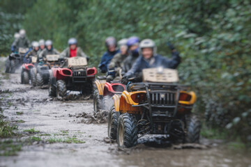 Group of riders riding atv vehicle on off road track, process of driving ATV vehicle, all terrain quad bike vehicle, during offroad competition, crossing a puddle of mud © tsuguliev