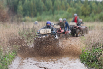 Group of riders riding atv vehicle on off road track, process of driving ATV vehicle, all terrain quad bike vehicle, during offroad competition, crossing a puddle of mud © tsuguliev