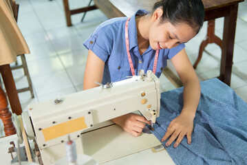 Asian female workers smile while sewing in the garment convection production room