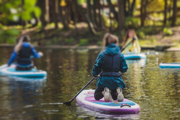 Group of sup surfers stand up paddle board, women stand up paddling together in the city river and...