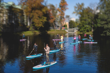 Group of sup surfers stand up paddle board, women stand up paddling together in the city river and...