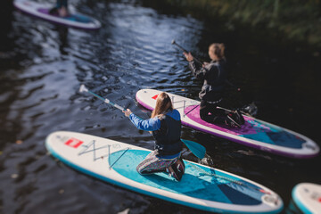 Group of sup surfers stand up paddle board, women stand up paddling together in the city river and...