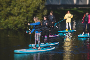 Group of sup surfers stand up paddle board, women stand up paddling together in the city river and...
