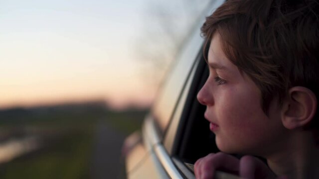 Close up from kid dreaming from an open car window while travelling
