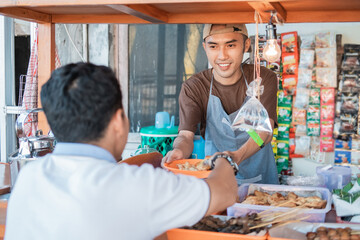 Asian young man seller the cart shop smiles when serving customers at the cart stall