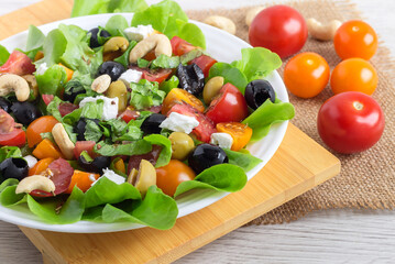 Greek fresh salad with tomatoes, olives, feta, lettuce in a white plate. Food for vegetarian.