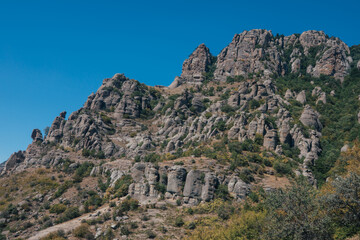 Fototapeta na wymiar Ridge of brown rocks covered with greenery against a blue sky