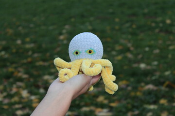 Knitted toy octopus on a background of autumn leaves