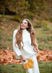 Fashionable woman laughing in autumn park. Beautiful Carefree curly girl in trendy fashion outfit smiling enjoy rest. Funny blonde portrait in park, fall concept. Fall outdoor.