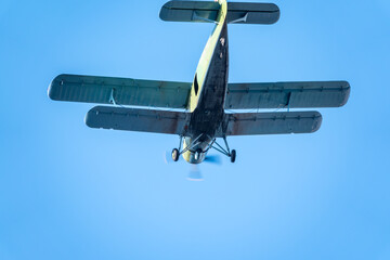 Retro green biplane plane in the blue sky