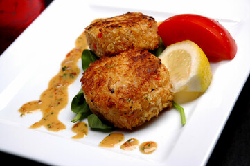 Crab Cakes with sauce, lemon and tomato garnish