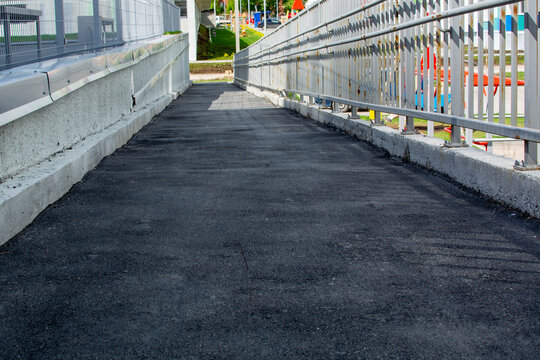 White Steel Ramp Construction With Plain Surface. Wall Mounted Hand Rails Both Sides For The Disabled In Urban Cityscape With Shadow. Outside Parapet For Access Path Environment For Disabled People.