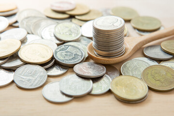 Coins stack on wooden spoon with sunlight  for money saving concept