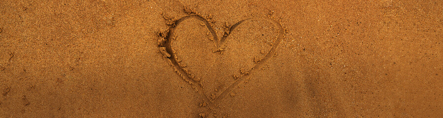 Banner hand drawing on orange brown sand at the beach sunset time with natural golden hour light . Love positive emotion concept