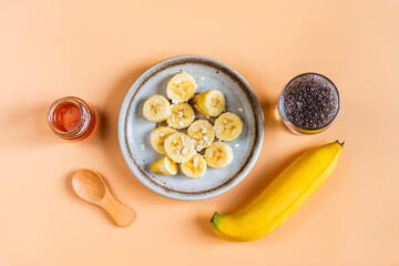Top view of sliced banana, chia seed and honey, Healthy food on pastel orange background