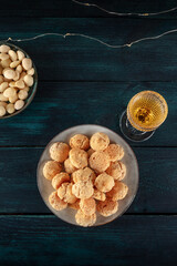 Amaretti, traditional Italian almond cookies, with a glass of Amaretto liqueur, overhead shot on a dark blue wooden background