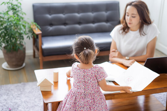 テレワークをする母親とそばで遊ぶ女の子