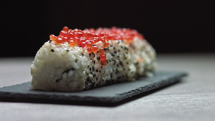 Chef cutting rolls of sushi with a knife on a stone board. - shot at a low angle. Beautiful female...