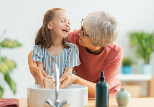 girl and her grandmother are washing hands