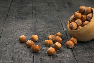 Hazelnuts are poured out of a wooden bowl on the table.