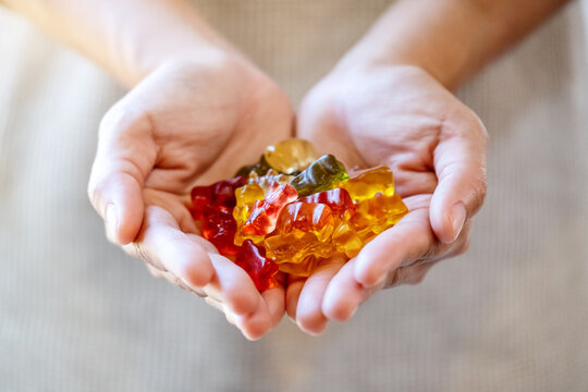 Closeup image of a woman holding colorful jelly gummy bears in hands