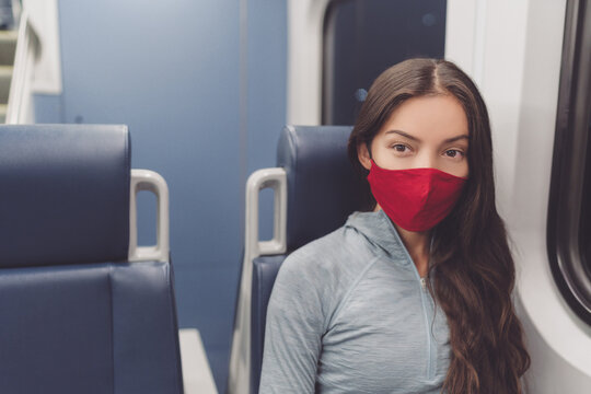 Woman wearing face mask in public transportation during coronavirus pandemic. Face mask wearing on train transport commuter. Multiracial woman passenger using cloth mouth covering on commute.