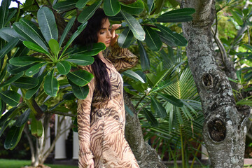Green leaves of bushes and a charming young woman in a white sundress on nature in the park