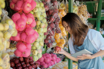 Close up of female shop assistant using digital tablet at his fruits shop when preparing