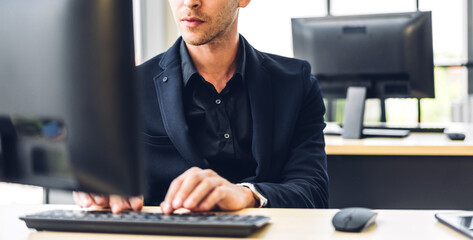 Handsome confident businessman relaxing looking at technology of desktop computer monitor while...