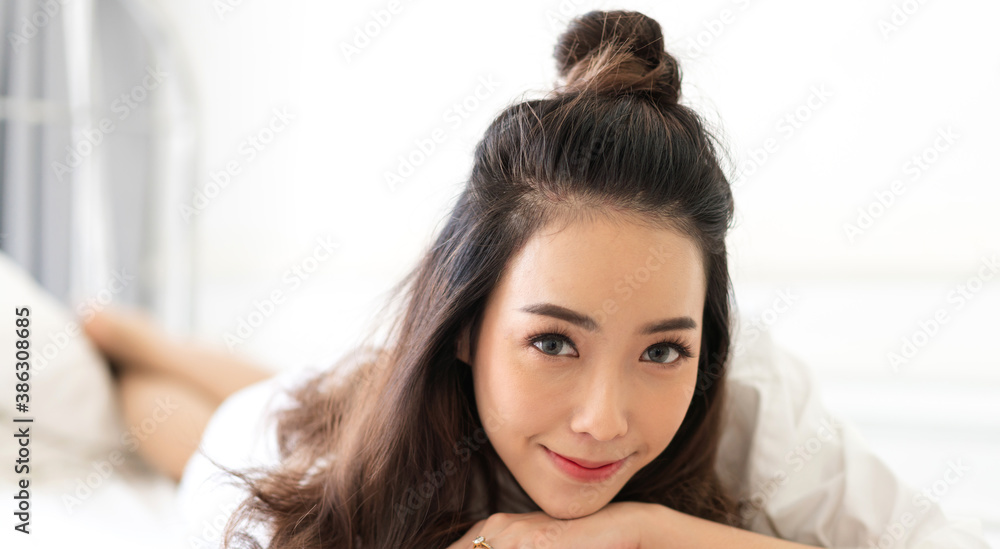 Wall mural Smiling of cheerful beautiful pretty asian woman clean fresh healthy white skin posing in white clothes.Girl felling relaxing and enjoy time on the bed at home.asia beauty