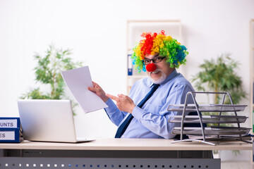 Old businessman clown working in the office