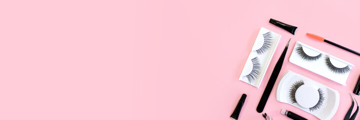 Different tools for eye lash extension on trendy pastel pink background. Fake eyelashes and tweezers. Knolling concept. Makeup cosmetics. Top view, copy space. Place for text and design. Banner.