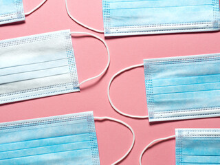 Medical protective mask on a pastel pink background. Individual, disposable surgical face mask flat...
