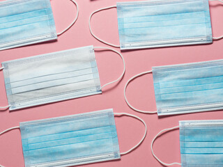 Medical protective mask on a pastel pink background. Individual, disposable surgical face mask flat...