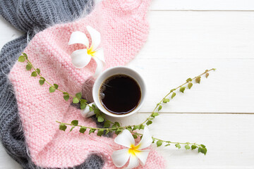 hot coffee espresso with knitting wool scarf of lifestyle woman relax and white flowers frangipani arrangement flat lay postcard style on background white wooden