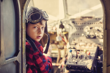 Portrait of a boy wearing aviator glasses sitting inside an old plane. Aviation dream