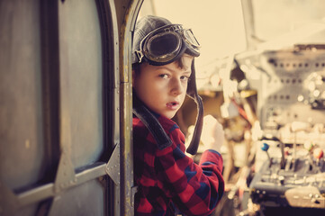 Portrait of a boy wearing aviator glasses sitting inside an old plane. Aviation dream