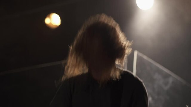 Long haired heavy metal musician head-banging and playing the guitar during live concert