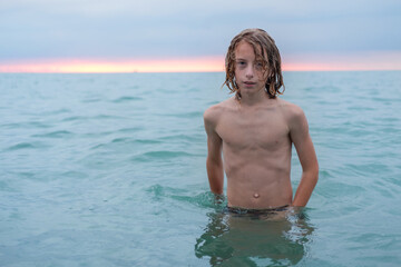 Young blonde teenage boy enjoys the sea at the beach.