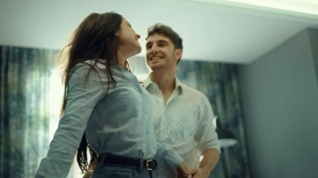 Excited couple having fun in hotel. Man making surprise for woman in bedroom.