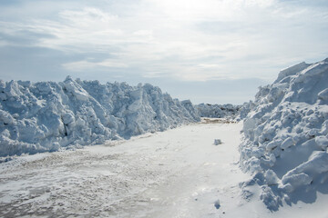 Large piles of snow on the side of the road for cars. High snowdrifts after a snowfall or blizzard