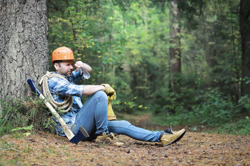 Male lumberjack in the forest. A professional woodcutter inspects trees for felling.