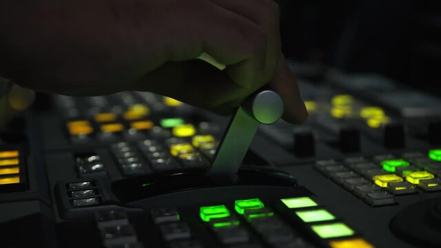 Television director is moving handle on a control panel during tv filming in studio