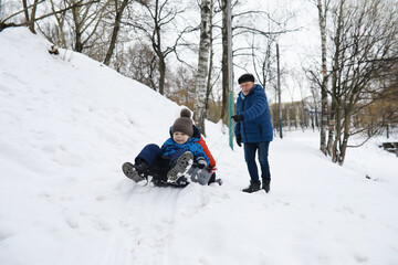 Children in the park in winter. Kids play with snow on the playground. They sculpt snowmen and slide down the hills.