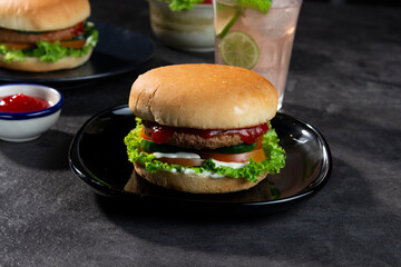 Delicious fresh meat burgers with tomato sauce and vegetables on a dark background.
